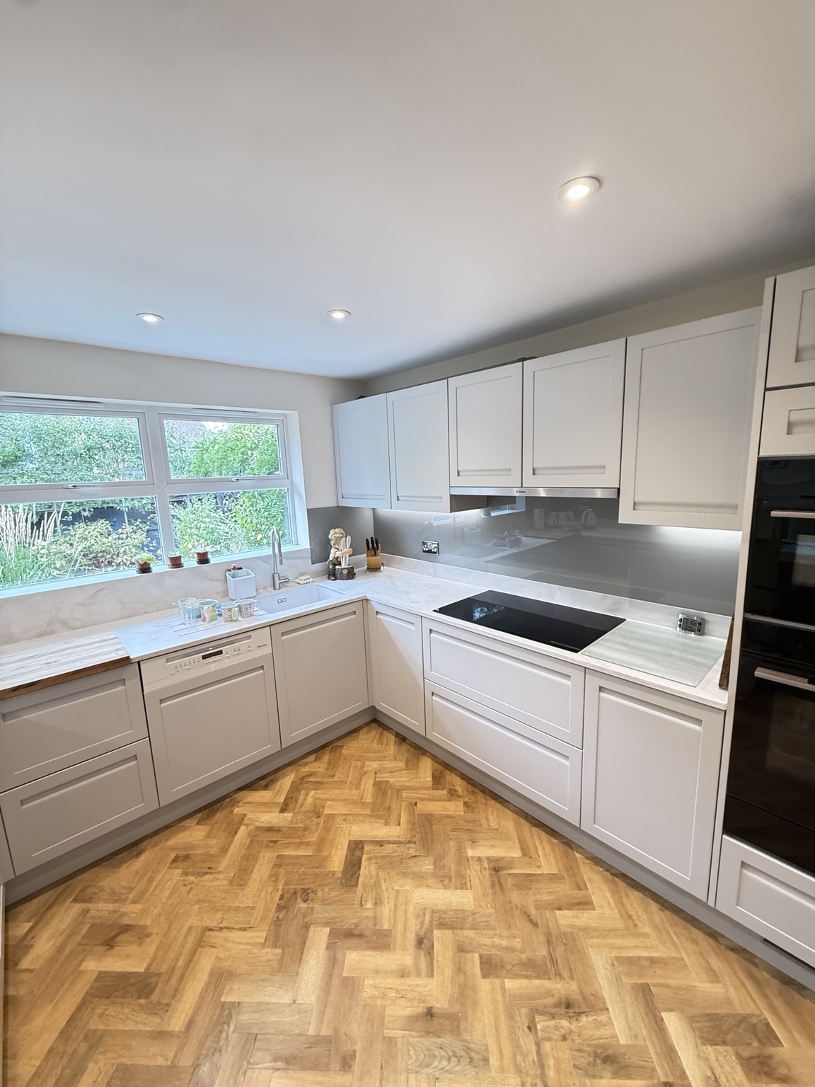Completed Worthing kitchen with light Shaker cabinetry, glass splashbacks and herringbone flooring