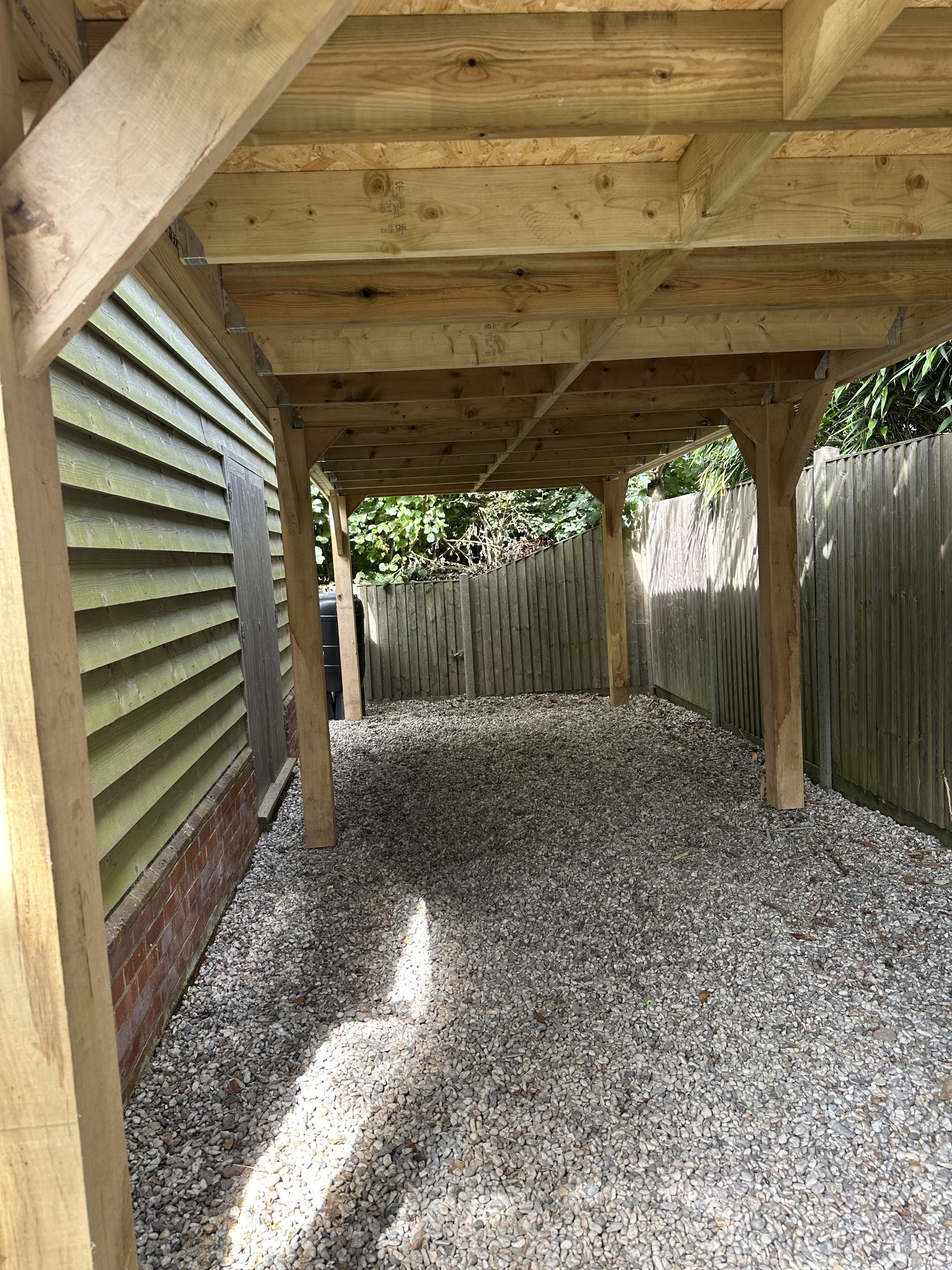 View beneath the finished carport showing timber roof framing, posts and bracing