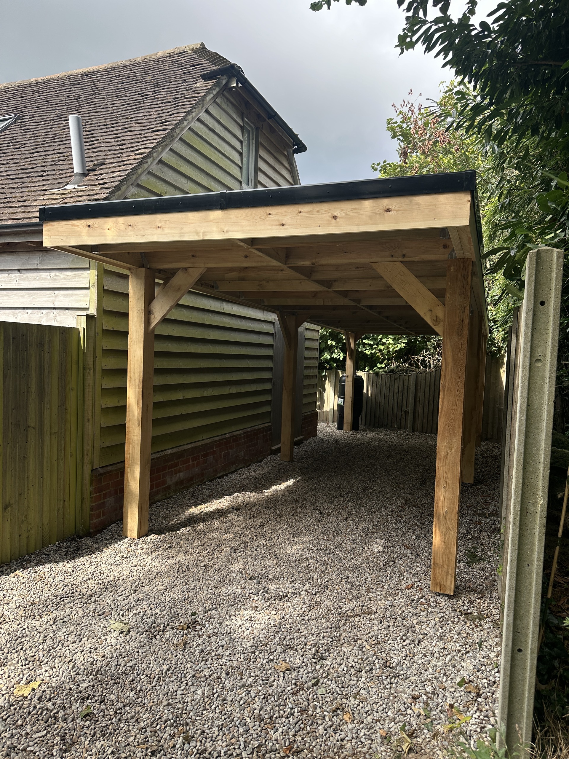 Finished oak carport with exposed posts and diagonal timber braces