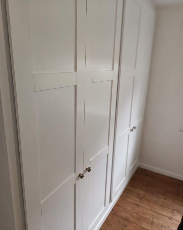 Completed fitted wardrobe with white Shaker doors and small round handles